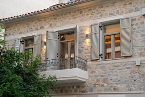 A stone building with shutters, a balcony, and a small garden area. - Nest in the City Apartment Home to Home Mgmt (Volos)