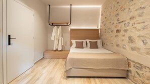 Ein Schlafzimmer mit einem Bett, einem Holzkopfstück, einer Steinwand und einer weißen Tür.