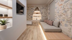 Ein modernes Wohnzimmer mit einer Steinsäule, Holzboden, einer Couch und einem kleinen Fenster mit Blick.