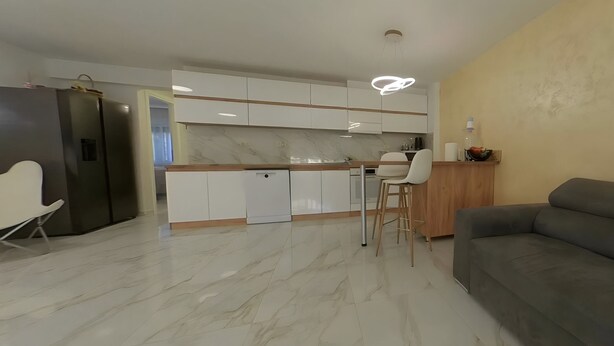 A modern kitchen with white cabinets, a marble countertop, and a unique circular light fixture. - Charming 3-Bedroom House Rental in Málaga, Spain (Málaga)