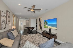 Ein Wohnzimmer mit einer Couch, einem Couchtisch, einem Fernseher und einem Deckenventilator.