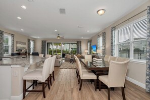 A spacious kitchen with a central island, dining area with chairs, and a living room with a sofa and coffee table. - Private Pool and Spa/10 Mins Disney/Ping Pong/Onsite Bar with views to Fireworks (Kissimmee)