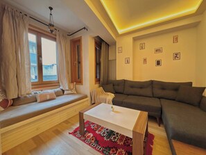 Ein Wohnzimmer mit einer Couch, einer Bank mit Kissen, einem Couchtisch und einem gemusterten Teppich.
