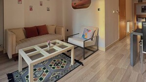 Un salon comprenant un canapé, un fauteuil, une table basse, un tapis et un tableau accroché au mur.