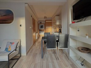 A compact living space with a kitchenette, dining area, and a TV mounted on the wall. - Taksim Square—1BR Suite 04 (Beyoğlu)