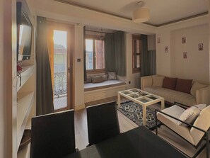 A living room with a sofa, a coffee table, a TV, and a balcony with a view. - Taksim Square—1BR Suite 04 (Beyoğlu)