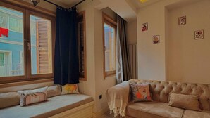 Una sala de estar con un sofá, una mesa de centro de vidrio y una ventana con cortinas.