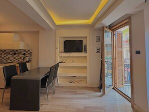 Eine moderne Küche mit gefliestem Fliesenspiegel, einer Essecke mit Tisch und Stühlen sowie einem an einer weißen Wand montierten Fernseher.