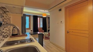 A compact kitchen with a sink, a kettle, and a small dining area with a chair and table. - Taksim Square—1BR Suite 01 (Beyoğlu)