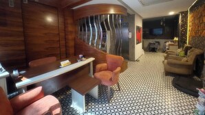 A modern interior with a curved wooden wall, a seating area with a bench and armchairs, a patterned floor, and a flat-screen TV in the background. - Taksim Square—1BR Suite 01 (Beyoğlu)