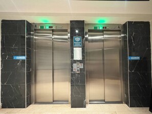 Two elevator doors with digital displays, a sign for a handicapped-accessible area, and a no-smoking sign. - Bright & Modern 2BR Apartment in Kağıthane (Kağıthane)