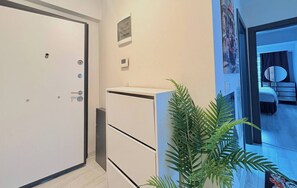 A hotel room with a bed, a nightstand, a mirror, and a potted plant. - Bright & Modern 2BR Apartment in Kağıthane (Kağıthane)