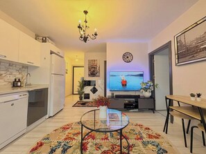 A modern living room with a TV, a dining area, and a kitchen. - Bright & Modern 2BR Apartment in Kağıthane (Kağıthane)