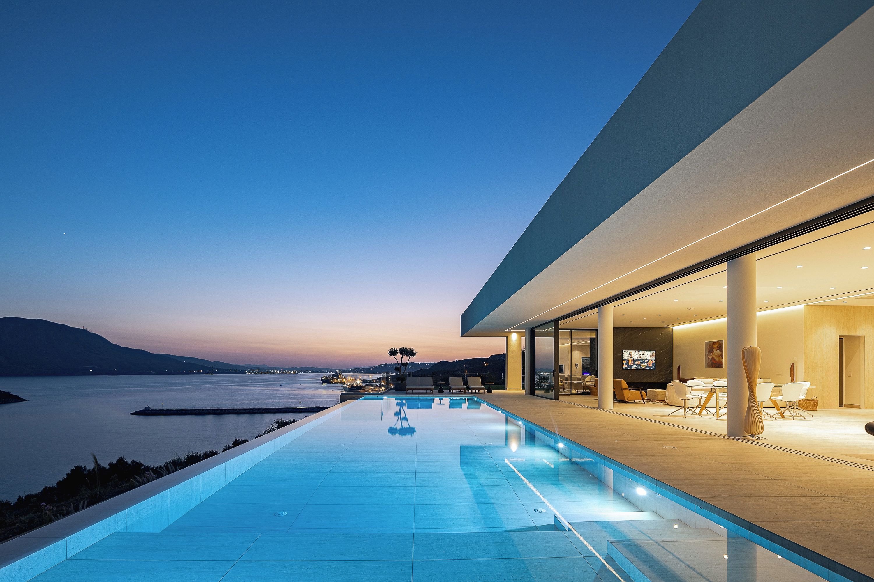 A modern building with an infinity pool overlooking a body of water.