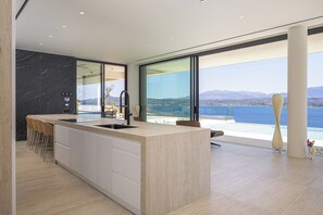 Eine moderne Küche mit einer großen Kochinsel, einer eingebauten Spüle und Blick auf das Meer.