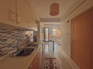 A modern kitchen with a tiled backsplash, stainless steel sink, and a coffee maker. - Taksim Square—1 Bedroom Suite 05 (Beyoğlu)