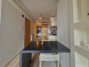 A narrow hallway leading to a kitchen with a dining table and a white chair. - Taksim Square—1 Bedroom Suite 05 (Beyoğlu)