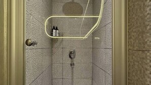 Eine kleine, geflieste Duschkabine mit Handbrause, Wandarmatur und einer Leuchte darüber.