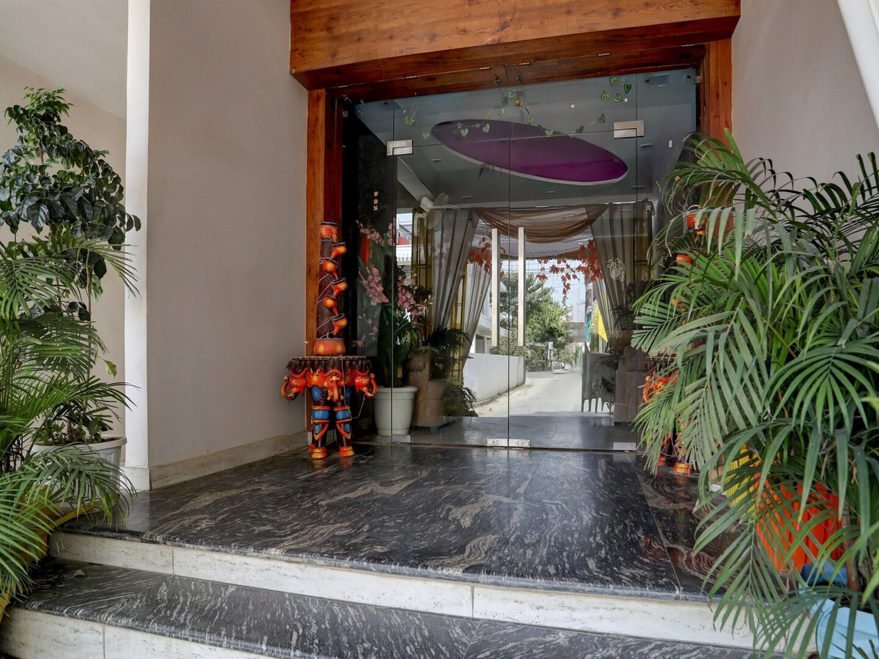 L’entrée d’un hôtel, avec un sol en marbre, des plantes en pot et une structure décorative.