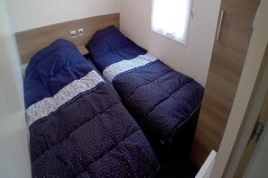 A small room with two beds, a window, and a door. - 3-bedroom holiday home in Loire (Saint-Jean-de-Monts)