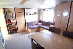 A compact RV interior with a kitchenette, a seating area, and a dining table. - 3-bedroom holiday home in Loire (Saint-Jean-de-Monts)