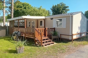 A mobile home with a porch, wooden steps, and a small garden area. - 3-bedroom holiday home in Loire (Saint-Jean-de-Monts)
