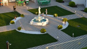 Un patio con una fuente central, zonas de estar verdes y un césped bien cuidado.