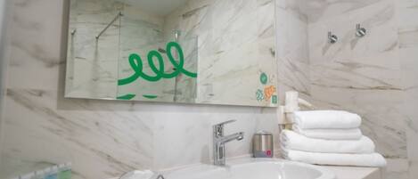 Une salle de bain avec un mur en marbre, un lavabo avec un miroir et un porte-serviettes.