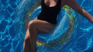 Una persona flotando en una piscina usando un aro inflable.