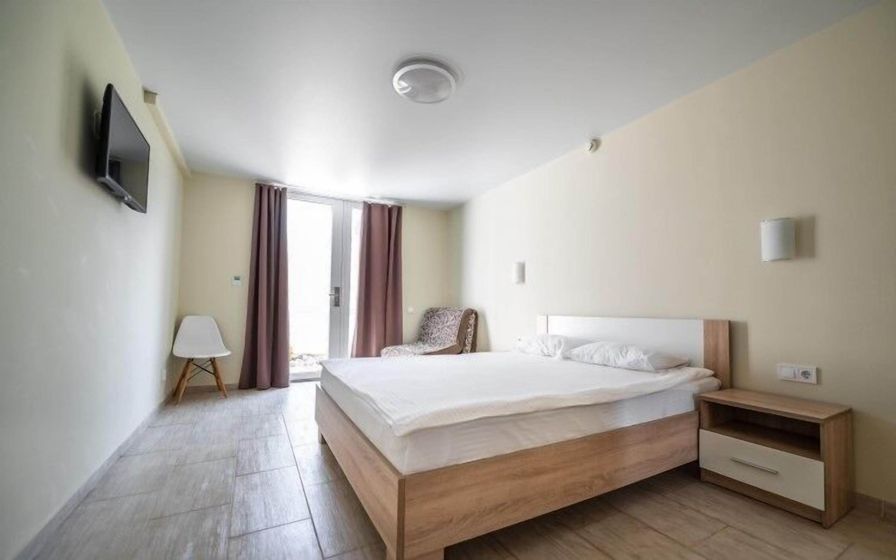 Une chambre d’hôtel équipée d’un lit, d’une table de chevet, d’une lampe, d’une chaise et d’un téléviseur fixé au mur.