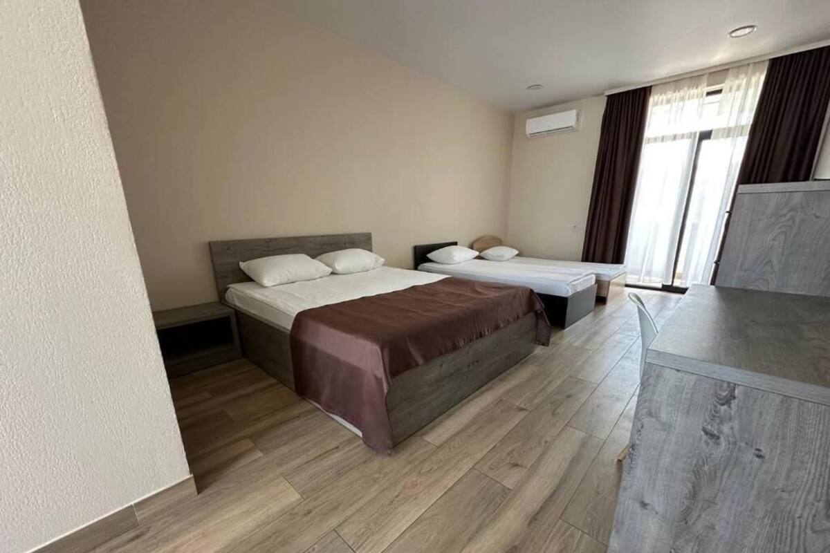 A hotel room with a large bed, a smaller bed, a desk, and a window with curtains.