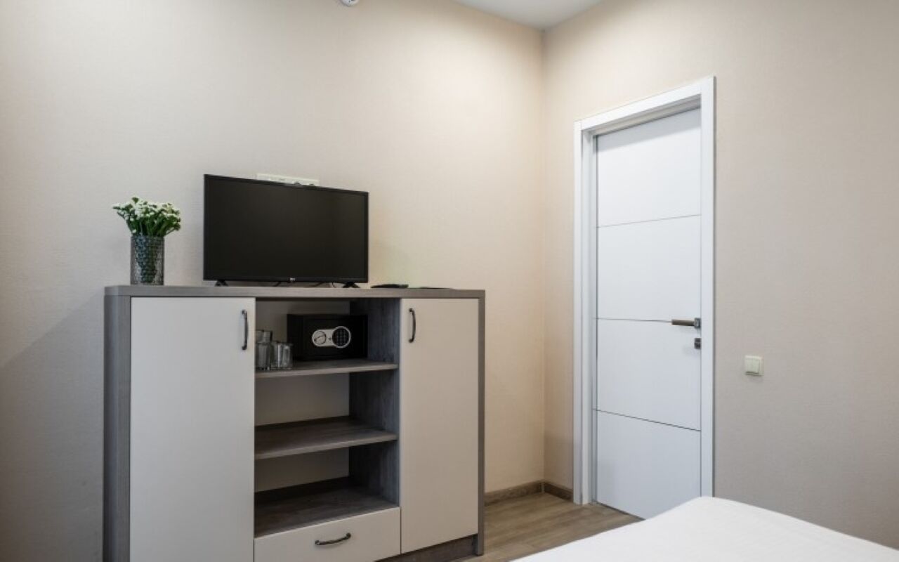 Quarto com cama, guarda-roupa, televisão e porta.