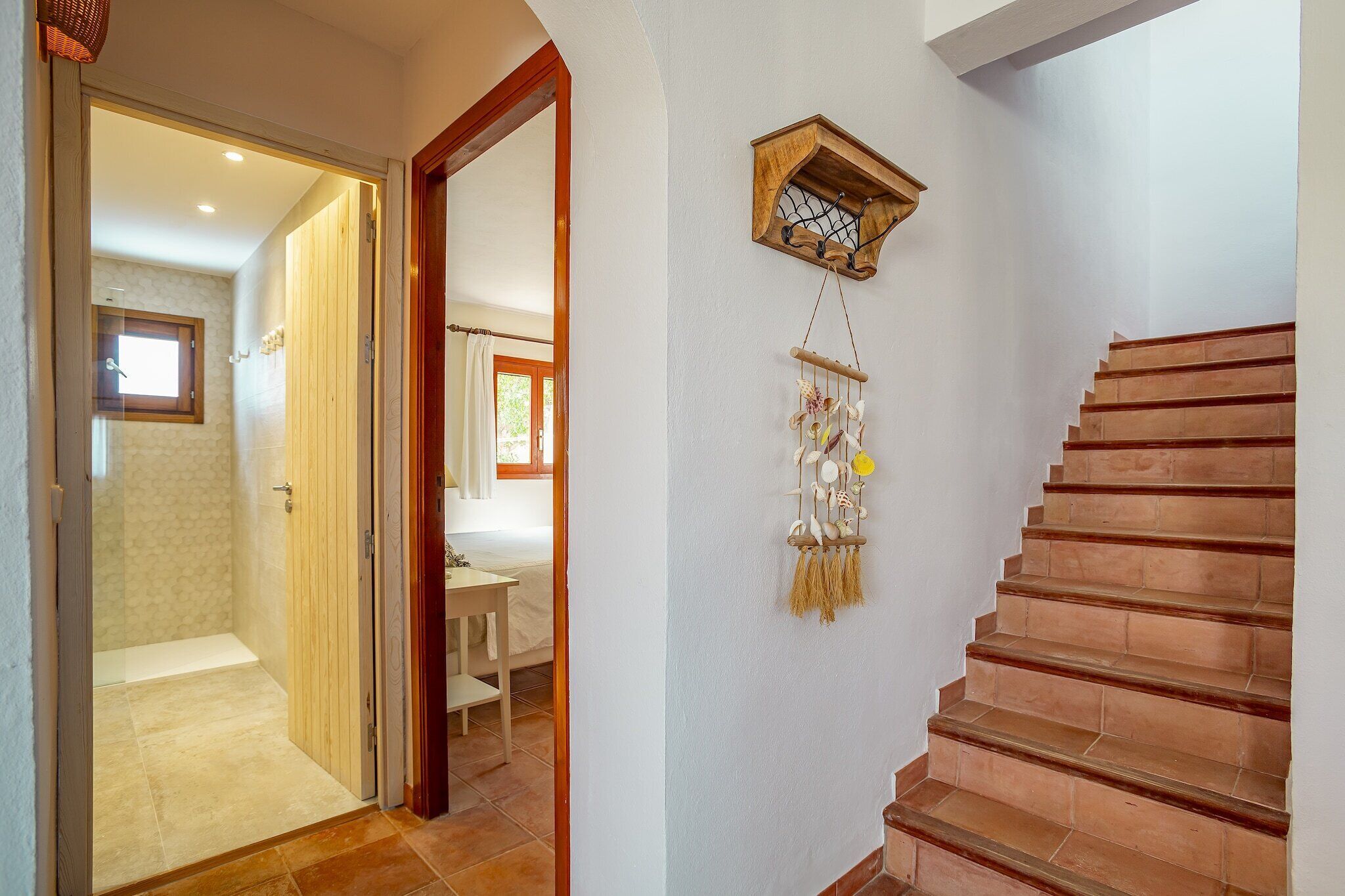 Un escalier avec une rampe en bois, une horloge fixée au mur et un attrape-rêves suspendu.