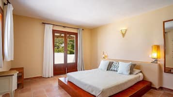 Une chambre à coucher comprenant un lit, un bureau, une chaise, une fenêtre avec des rideaux et un luminaire fixé au mur.