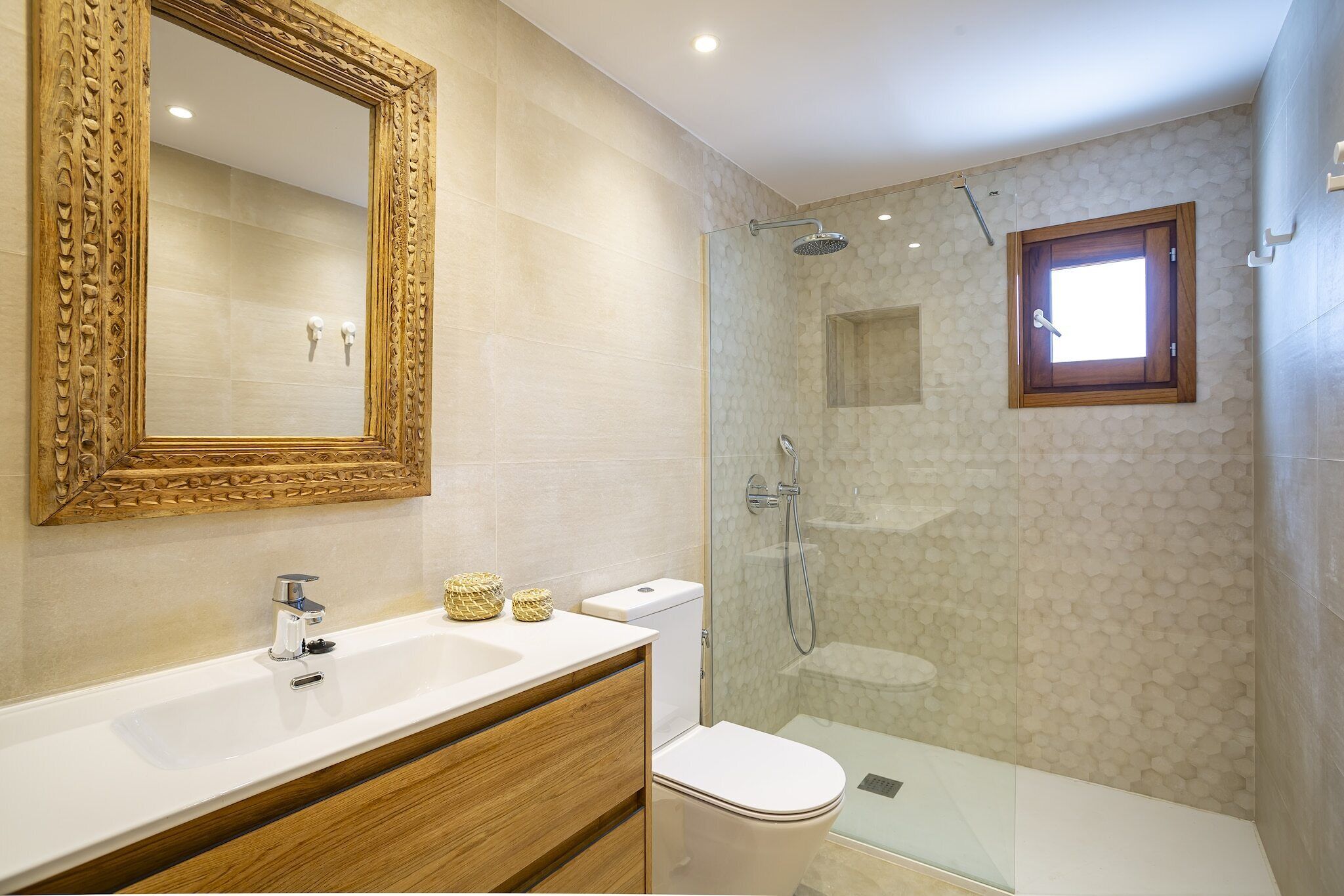 A bathroom with a large mirror, a sink, a toilet, and a shower area.