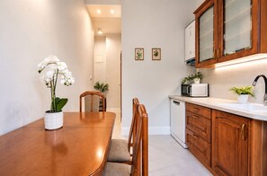A kitchen with wooden cabinets, a microwave, a sink, and a dining table with chairs. - Kalina Apartment Old Town Gdańsk (Gdańsk)