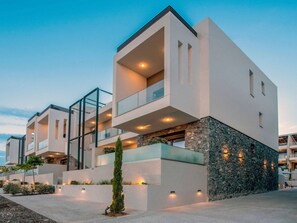 A modern multi-story building with balconies, stone accents, and outdoor lighting. - Two Bedroom Suite Tatiana in Nikiti (Nikiti city)