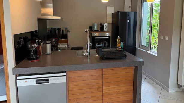 A modern kitchen with a central island, built-in dishwasher, and pendant lighting. - Le Verger Secret – Mobility Lease at Lyon’s Doorstep, Ideal for Business Stays (Rillieux-la-Pape)