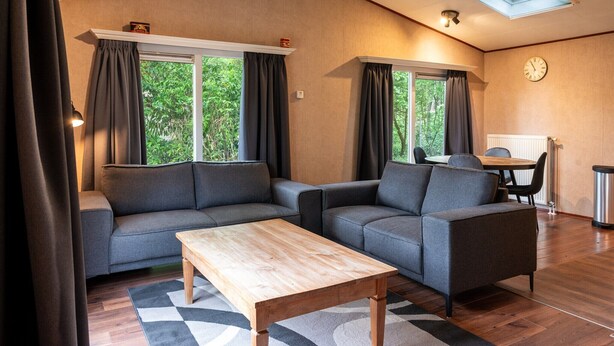 Een moderne woonkamer met twee banken, een houten salontafel en een dakraam.