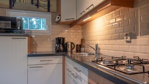 Een moderne keuken met witte kasten, een gasfornuis, een koffiezetapparaat en een magnetron.