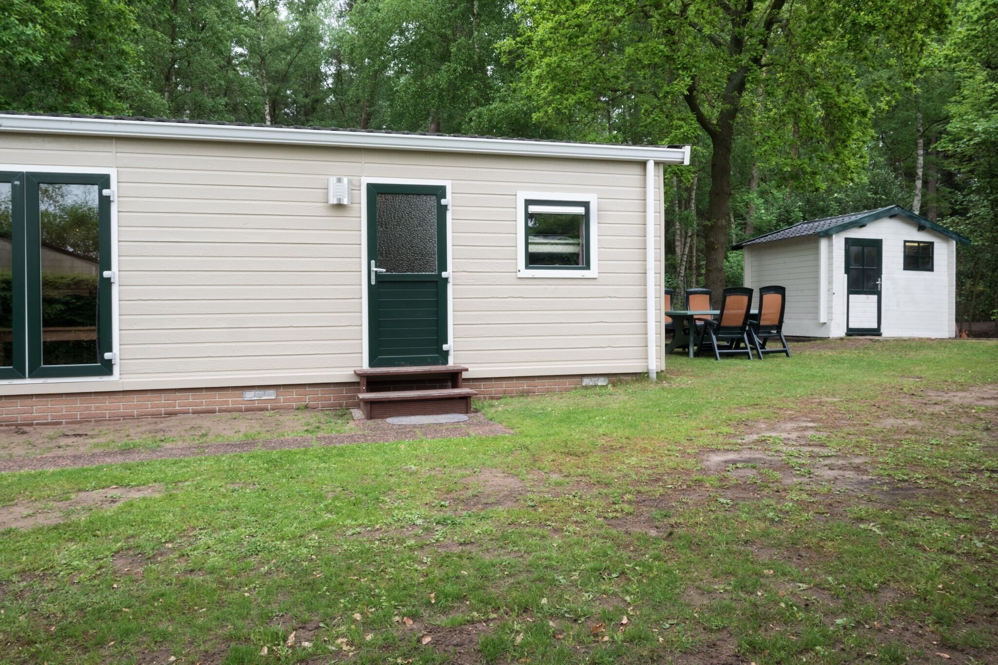 A single-story building with a front door, a small porch, and a patio area with chairs.