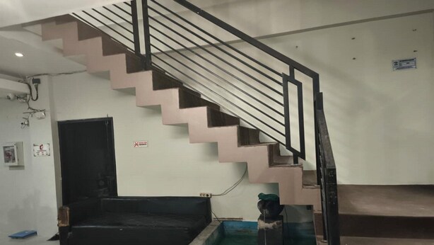 A staircase with a black railing, a black sofa, and a small water feature with lights.