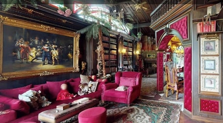 A room with a large classical painting, a red sofa, a bookshelf, and a red armchair.. Apartment "Haus Toskana" with Private Pool, Wi-Fi, and Air Conditioning