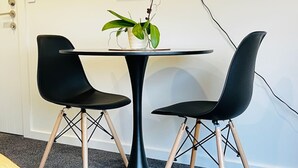 A modern room with a round table, two black chairs, and a potted plant. - Private Luxury on Blue Dun (Taupō)