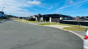 A residential street with modern houses, a clear sky, and a parked car. - Private Luxury on Blue Dun (Taupō)