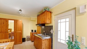 Cucina con pensili in legno, un lavello, un fornello e una finestra.