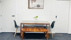 A room with a wooden table, two chairs, a small plant, and a painting on the wall.