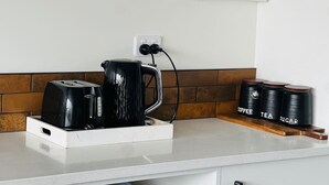 A kitchen counter with a coffee maker, a toaster, and three containers labeled coffee, tea, and sugar. - Penny Retreat with 1 Bedroom (Taupō)