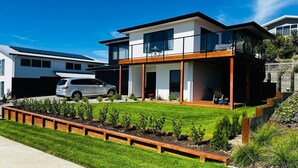 A modern two-story house with a balcony, a driveway, and a well-maintained lawn. - Penny Retreat with 1 Bedroom (Taupō)