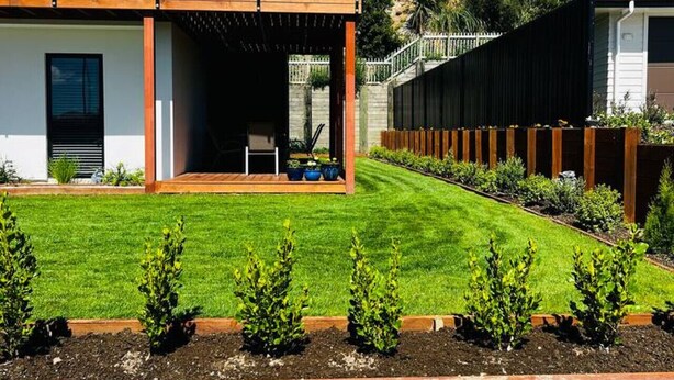 A modern two-story house with a covered patio, a well-maintained lawn, and a wooden fence. - Penny Retreat with 1 Bedroom (Taupō)